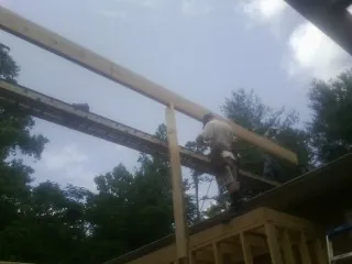 Carpenter setting a ridge beam over a new addition frame — Ice Dam Removal by Roofing Brothers in Shutesbury