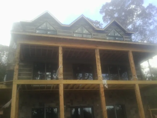 Dormers and porch framing on a large log home under construction — Roof Coating work by our crew in Shutesbury