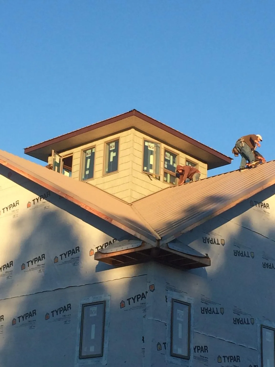 Roofers working around a rooftop cupola on a new metal roof at sunset — Roof Waterproofing in Shutesbury by Roofing Brothers
